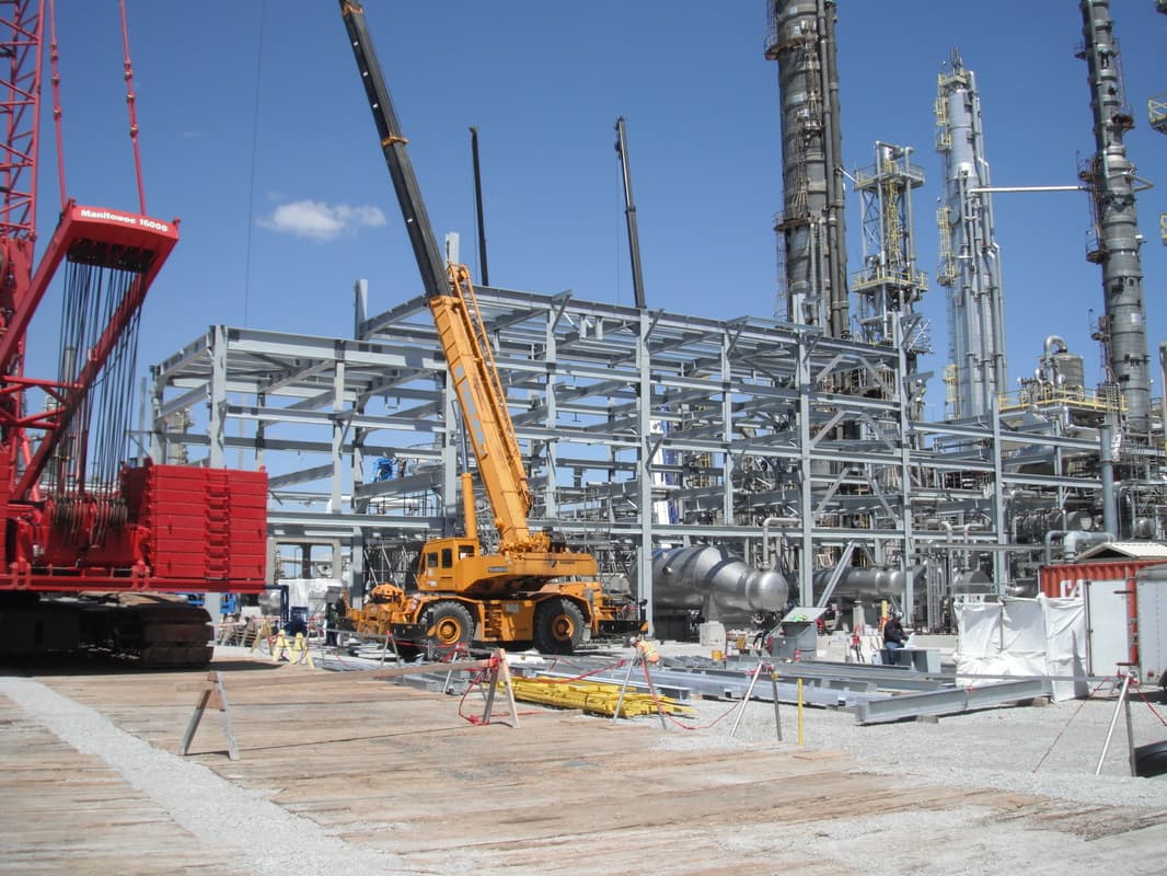 Cranes setting structural steel at an industrial site